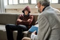 Restless teenage boy on sofa next to psychotherapist