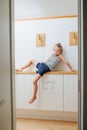 Restless thin little boy sitting on a corridor shelf, frustrated