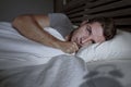 Restless worried young attractive man awake at night lying on bed sleepless having eyes opened depressed suffering insomnia sleepi Royalty Free Stock Photo