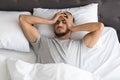 Restless young Arab guy waking up in the morning with headache Royalty Free Stock Photo