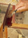 Restoration of old furniture. A man`s wrinkled hand of an elderly man with a paint brush applies varnish to the wooden surface of Royalty Free Stock Photo