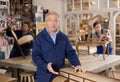 Ederly craftsman polishes tabletop of old chest of drawers with rounded drawers with soft cloth Royalty Free Stock Photo