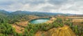 Restoration works in copper mining area with lake in open mine pit and spoil heaps covered with pine trees