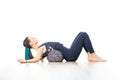 Restorative yoga with a bolster. Young sporty attractive woman in bright white yoga studio, lying on bolster cushion