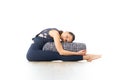 Restorative yoga with a bolster. Young sporty attractive woman in bright white yoga studio, lying on bolster cushion Royalty Free Stock Photo