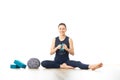 Restorative yoga with a bolster. Young sporty female yoga instructor in bright white yoga studio, smiling cheerfully