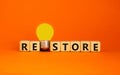 Restore symbol. Wooden cubes with the word `restore`. Yellow light bulb. Beautiful orange background. Business and restore conce