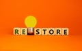 Restore symbol. Wooden cubes with the word `restore`. Yellow light bulb. Beautiful orange background. Business and restore conce