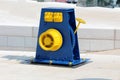 Restored vintage retro blue and yellow cast iron pulley wheel mounted on traditional stone tiles pier used for working with small