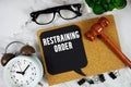 Restraining Order text on speech bubble with alarm clock and wooden gavel on marble background Royalty Free Stock Photo