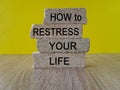 Restress your life symbol. Concept words How to restress your life on brick blocks. Beautiful wooden table yellow background.