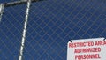 Restricted area, authorized personnel only sign in USA. Red letters, keep off warning on metal fence, United States border symbol