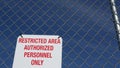 Restricted area, authorized personnel only sign in USA. Red letters, keep off warning on metal fence, United States border symbol