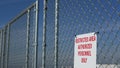 Restricted area, authorized personnel only sign in USA. Red letters, keep off warning on metal fence, United States border symbol