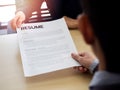 Resume or CV paper. Applicant`s hand giving resume to employer for review the profile of the applicant
