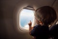 Resumption of flights, opening of borders concept. a small child looks at the ocean from the window of a flying plane. the first Royalty Free Stock Photo