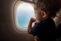 Resumption of flights, opening of borders concept. a small child looks at the ocean from the window of a flying plane. the first Royalty Free Stock Photo