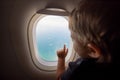 Resumption of flights, opening of borders concept. a small child looks at the ocean from the window of a flying plane. the first Royalty Free Stock Photo