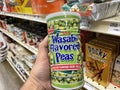 Retail store shelves hand holding can of wasabi peas