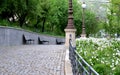 Retaining wall concrete path of granite cubes park bench wooden lamp railing gray metal decorative white flowers in flowerbed Royalty Free Stock Photo