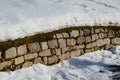 Retaining wall made of granite bricks by the road. the snow fit all around, only the wall remained visible in its beautiful textur