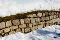 Retaining wall made of granite bricks by the road. the snow fit all around, only the wall remained visible in its beautiful textur