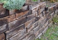 The retaining wall made of wooden sleepers is wooden and forms the edge of the perennial flowerbed. landscaping of brown palisade Royalty Free Stock Photo