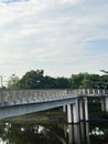pedestrian bridge made of concrete and metal railing, stretching across a dark, reflective body of water, possibly a canal, lake Royalty Free Stock Photo