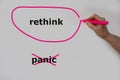 Rethink as an alternative to panic is written on a white wall by one hand, Rethink is circled with a pink pen and panic has been c