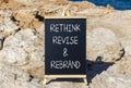 Rethink revise rebrand symbol. Concept word Rethink Revise and Rebrand on beautiful blackboard. Beautiful red stone background.