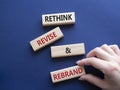 Rethink Revise and Rebrand symbol. Wooden blocks with words Rethink Revise and Rebrand. Businessman hand. Beautiful deep blue