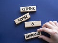 Rethink Revise and Rebrand symbol. Wooden blocks with words Rethink Revise and Rebrand. Businessman hand. Beautiful deep blue