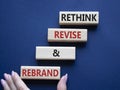 Rethink Revise and Rebrand symbol. Wooden blocks with words Rethink Revise and Rebrand. Businessman hand. Beautiful deep blue