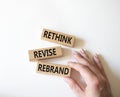 Rethink Revise Rebrand symbol. Wooden blocks with words Rethink Revise Rebrand. Beautiful white background. Businessman hand.