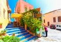 Rethymnon, Island Crete, Greece, - July 1, 2016: Cosy cretan small cafe with flowers outside with and waitress is putting a menu