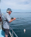 Retired adult man fishing on charter boat, catching a snapper - Royalty Free Stock Photo