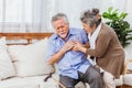 Retired Asian senior elderly husband pain from heart attack disease or illness with serious or worried wife take care at home. Royalty Free Stock Photo