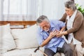 Retired Asian senior elderly husband pain from heart attack disease or illness with serious or worried wife take care at home. Royalty Free Stock Photo