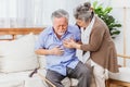 Retired Asian senior elderly husband pain from heart attack disease or illness with serious or worried wife take care at home. Royalty Free Stock Photo