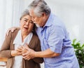 Retired Asian senior elderly wife pain from heart attack disease or illness with serious or worried husband take care at home. Royalty Free Stock Photo