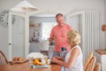 Retired Couple At Home In Kitchen Eating Breakfast Together