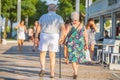 Retired couple is relaxing and walking along a sunny summer street on vacation during sunset in Riccione