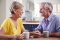 Retired Couple Sitting Around Table At Home Having Morning Coffee Together Royalty Free Stock Photo