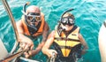 Retired couple taking happy selfie in tropical sea excursion with life vests and snorkel masks - Boat trip snorkeling