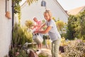 Retired Couple At Work Watering And Caring For Plants In Garden At Home