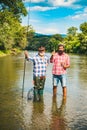 Retired dad and mature bearded son. Happy bearded fishers in water. Men relaxing nature background. Brutal man stand in Royalty Free Stock Photo