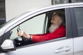 Senior  man with long beard driving gray car Royalty Free Stock Photo