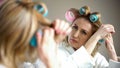 Retired female fixing hair curlers and preparing for romantic date, appearance Royalty Free Stock Photo