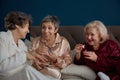 Retired female friends applying nail polish while having playful time at home Royalty Free Stock Photo