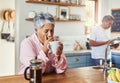 The retired life. a carefree elderly woman sitting at a table in the kitchen drinking coffee and about to sneeze. Royalty Free Stock Photo